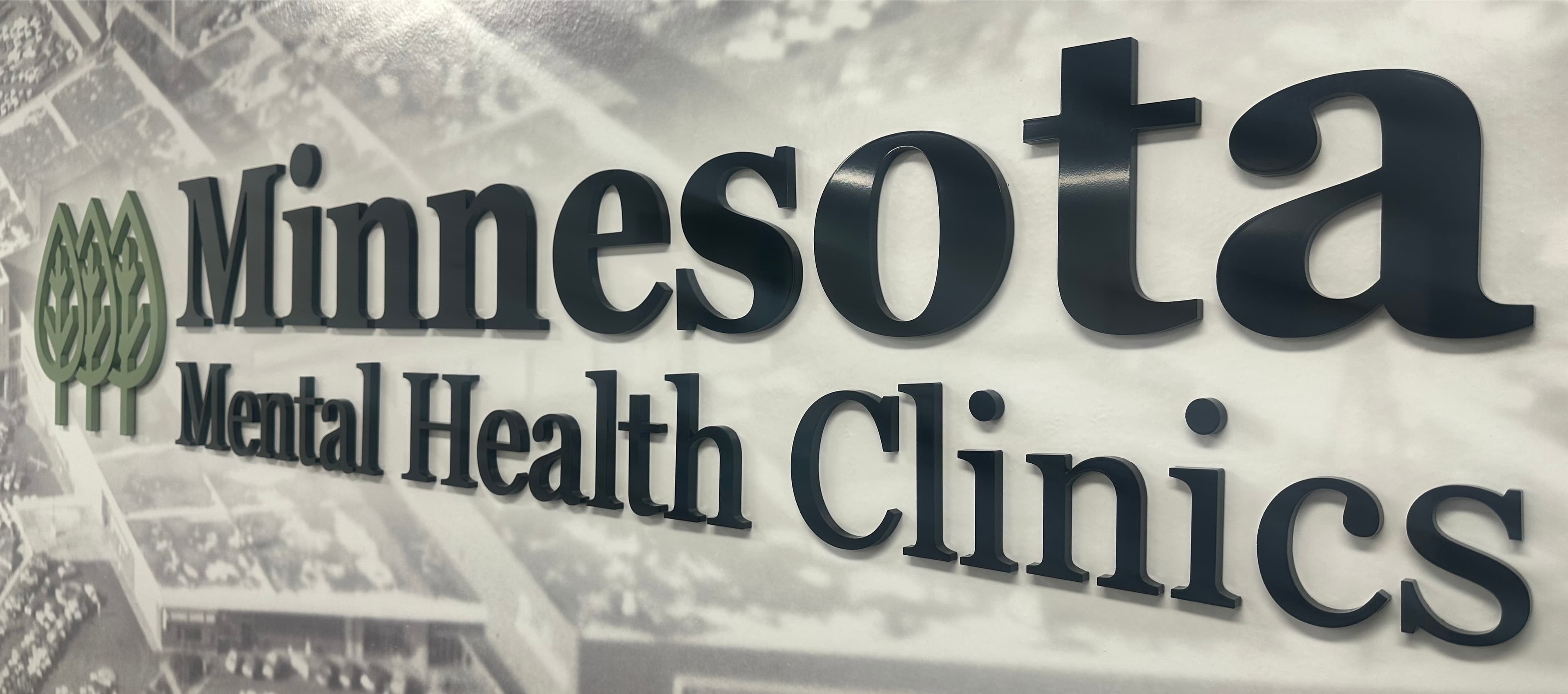 Minnesota Mental Health Clinics lobby sign β the MMHC name and green tree logo mounted on a wall at one of our Minnesota clinic locations