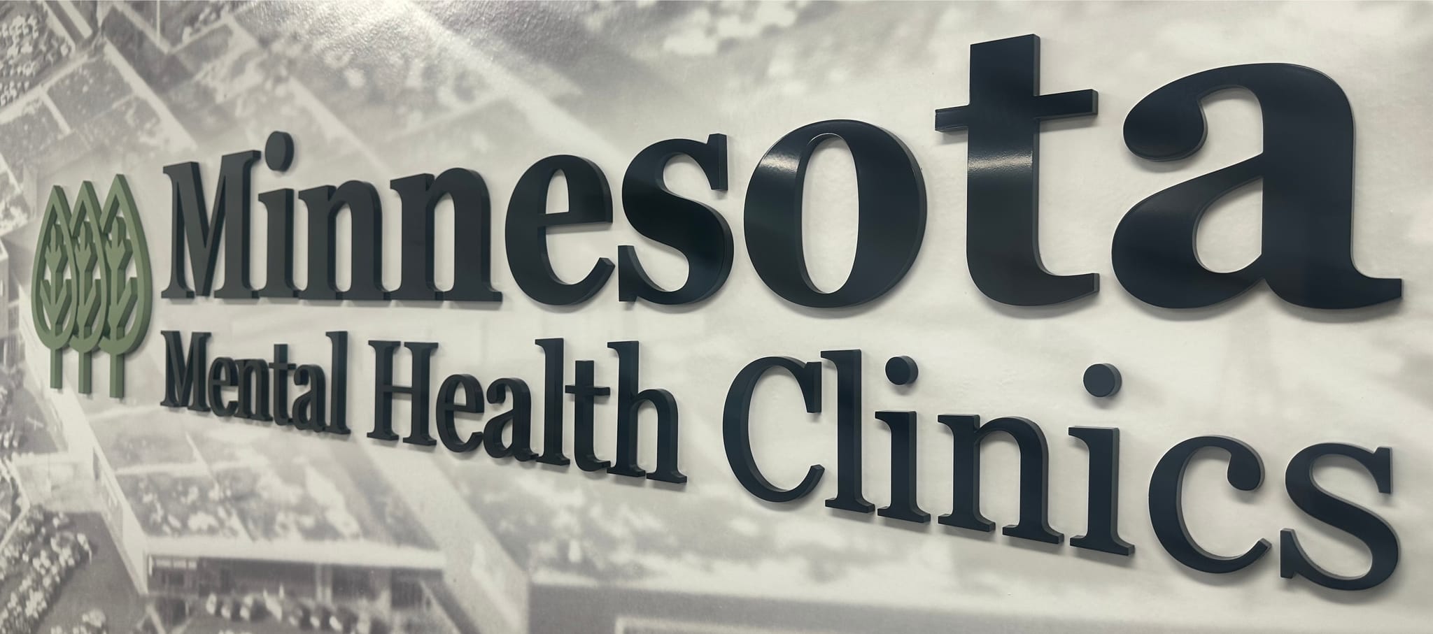 Minnesota Mental Health Clinics lobby sign β the MMHC name and green tree logo mounted on a wall at one of our Minnesota clinic locations